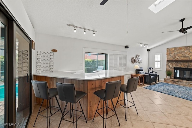 kitchen with a ceiling fan, a breakfast bar area, a peninsula, light countertops, and light tile patterned flooring