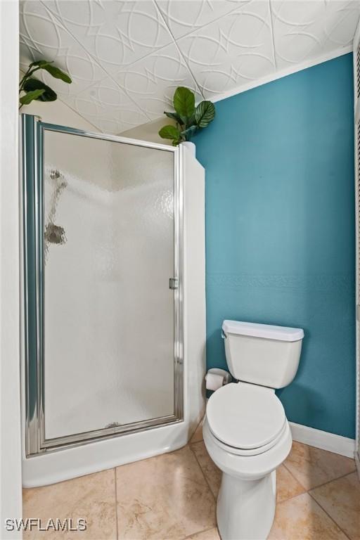 bathroom with tile patterned floors, crown molding, an enclosed shower, and toilet