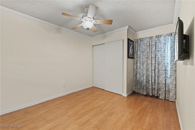 unfurnished bedroom with a textured ceiling, ceiling fan, crown molding, light hardwood / wood-style flooring, and a closet