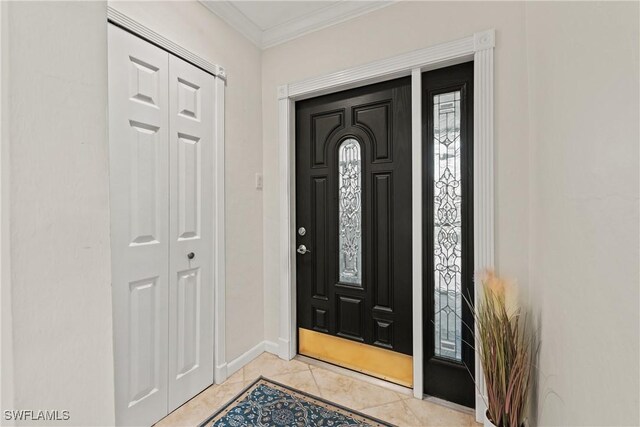 entryway with light tile patterned floors, ornamental molding, and baseboards