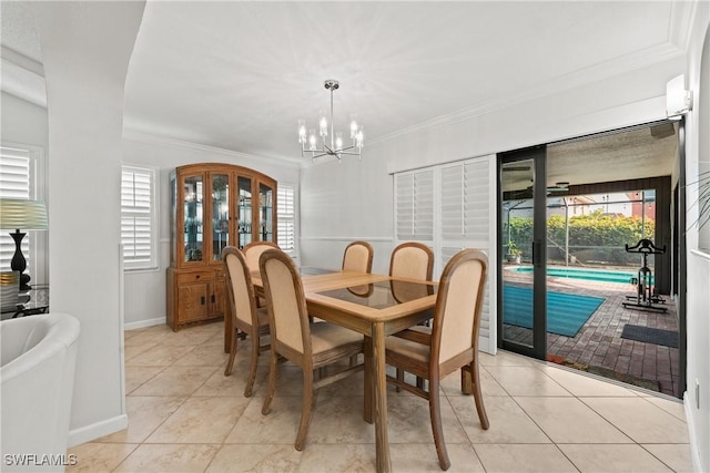 dining space with light tile patterned floors, plenty of natural light, ornamental molding, and a notable chandelier