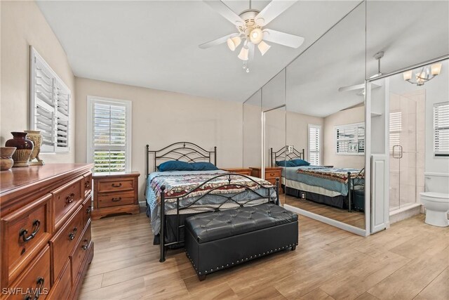 bedroom with light wood-type flooring, ensuite bath, ceiling fan, and vaulted ceiling