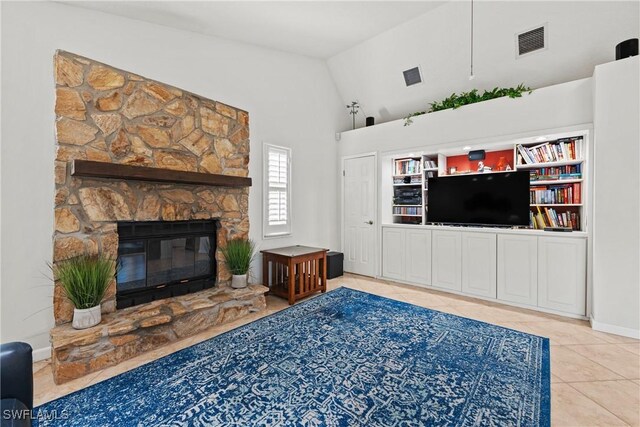 living room featuring a stone fireplace, built in features, tile patterned flooring, and lofted ceiling