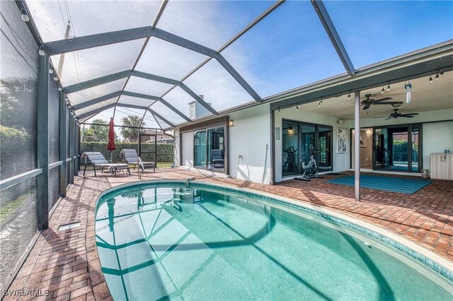 view of swimming pool featuring a patio, glass enclosure, and ceiling fan