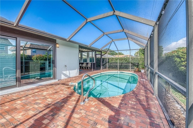 outdoor pool featuring glass enclosure and a patio