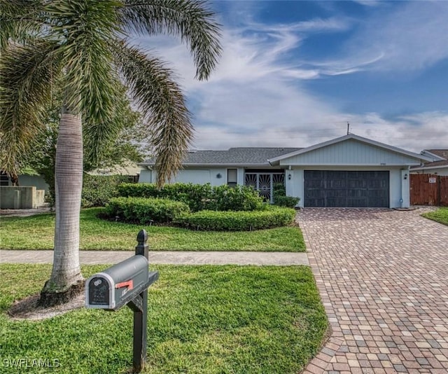 ranch-style home with a front lawn, fence, a garage, stucco siding, and decorative driveway
