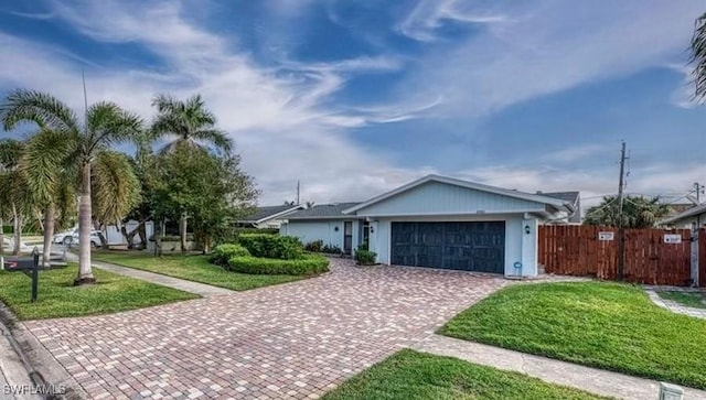 single story home with an attached garage, fence, decorative driveway, and a front lawn