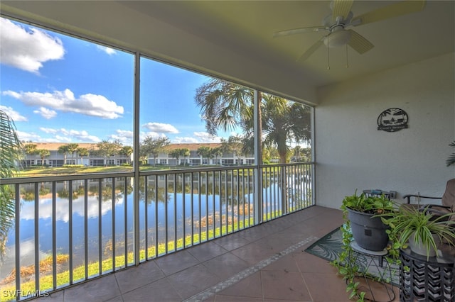 unfurnished sunroom with ceiling fan and a water view