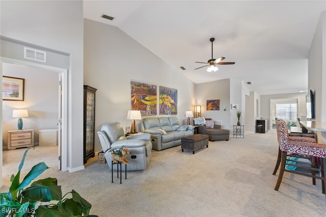 carpeted living room with ceiling fan and high vaulted ceiling