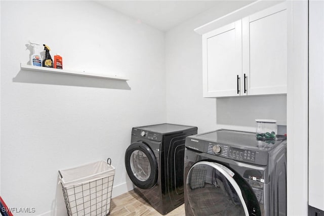 washroom with washer and clothes dryer, cabinets, and light hardwood / wood-style flooring