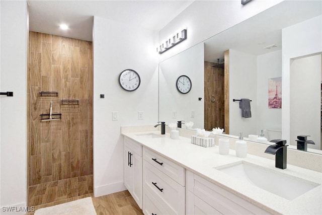 bathroom featuring toilet, hardwood / wood-style floors, vanity, and a tile shower