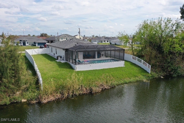 back of house with a fenced in pool, glass enclosure, a yard, and a water view