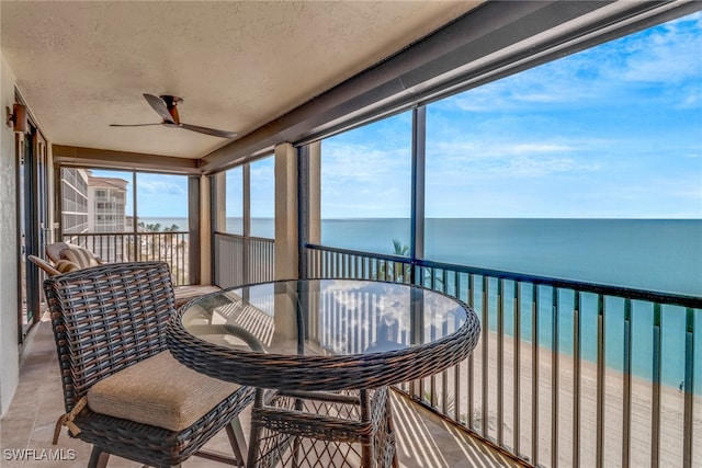 sunroom / solarium with a view of the beach, a water view, and ceiling fan