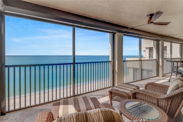 sunroom / solarium featuring a view of the beach, a water view, and ceiling fan