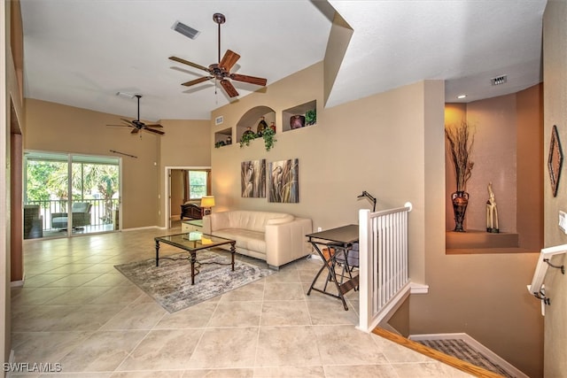 living room with ceiling fan, a towering ceiling, and light tile patterned floors