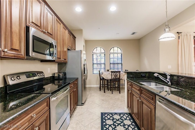 9028 Alturas St Unit 3204, Naples, FL 34113 - kitchen with stainless steel appliances, a sink, dark stone counters, light tile patterned floors, and hanging light fixtures