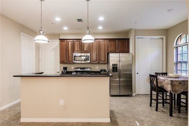 kitchen with stainless steel appliances, pendant lighting, a kitchen bar, a kitchen island with sink, and light tile patterned flooring