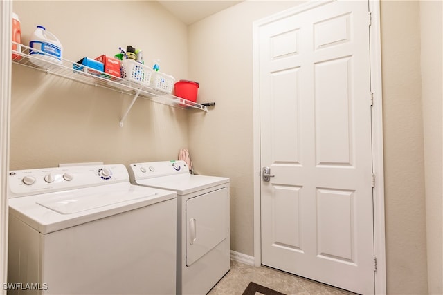 laundry area with washer and clothes dryer and light tile patterned flooring