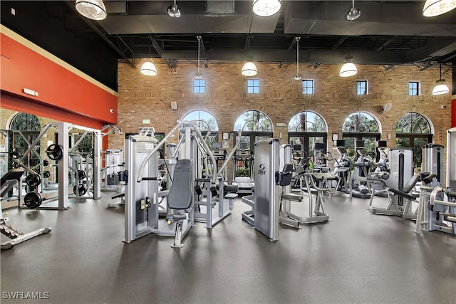 gym with a towering ceiling and brick wall