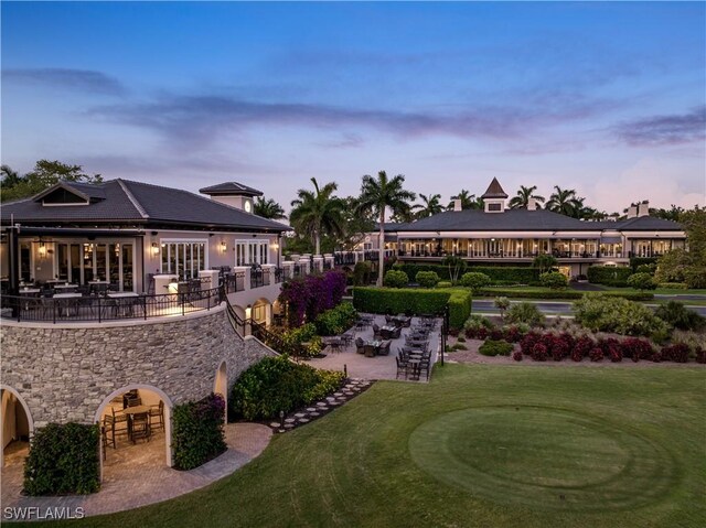 5100 Baybridge Blvd Unit 1601, Estero, FL 33928 - back of house at dusk with a patio, a lawn, stone siding, and a putting green