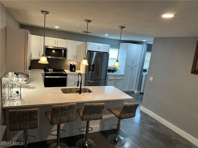 kitchen featuring white cabinetry, sink, hanging light fixtures, stainless steel appliances, and decorative backsplash