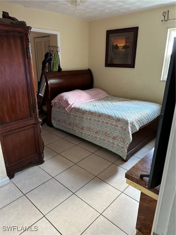 tiled bedroom with a textured ceiling and a closet