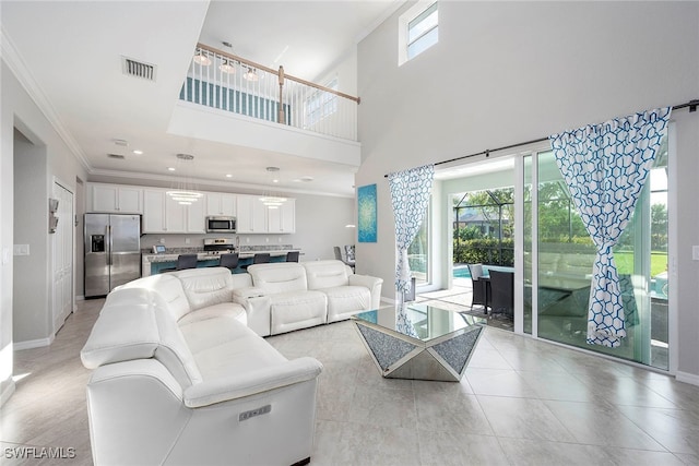 living room featuring ornamental molding, a towering ceiling, and a healthy amount of sunlight