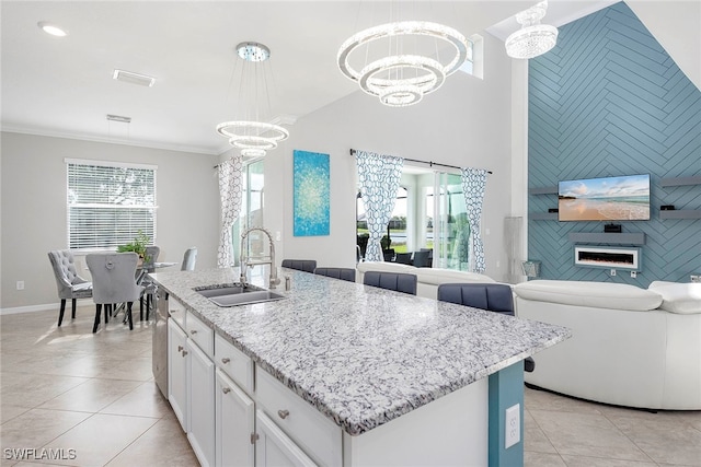 kitchen with white cabinetry, sink, an island with sink, decorative light fixtures, and light tile patterned floors