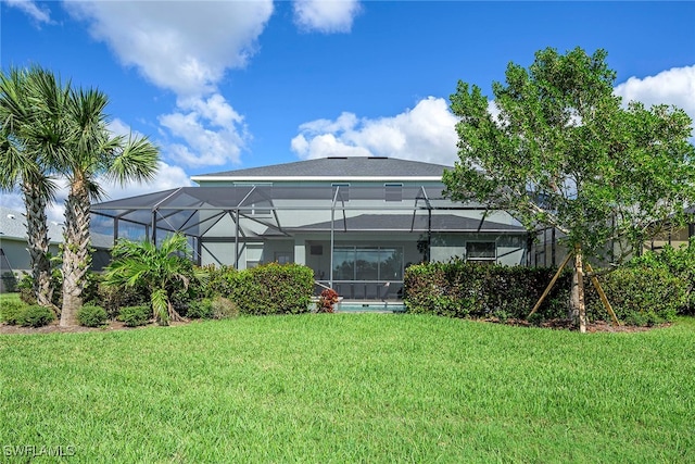 rear view of house with a lawn and a lanai