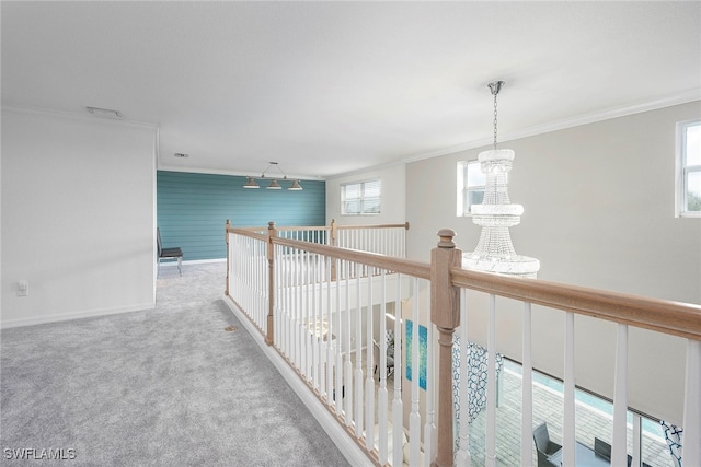 hallway with a chandelier, carpet floors, crown molding, and track lighting