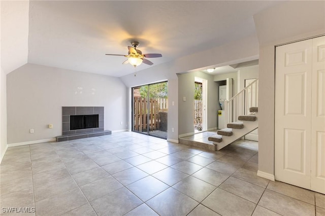 unfurnished living room featuring ceiling fan, lofted ceiling, light tile patterned floors, and a tiled fireplace