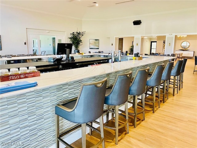 kitchen with a kitchen bar, light wood-style floors, and ornamental molding