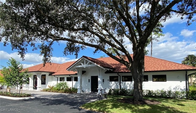 mediterranean / spanish-style house with aphalt driveway, stucco siding, a tile roof, and a front lawn