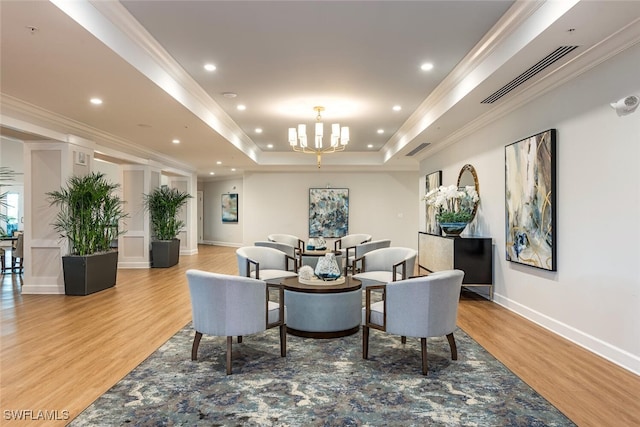 dining room featuring visible vents, crown molding, a raised ceiling, and light wood-style floors