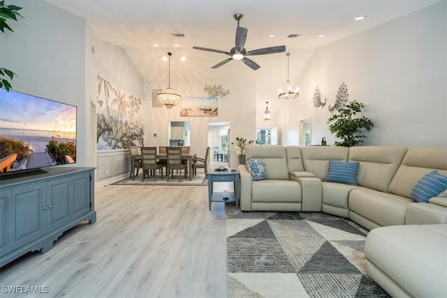 living room with visible vents, ceiling fan with notable chandelier, recessed lighting, light wood-style floors, and high vaulted ceiling