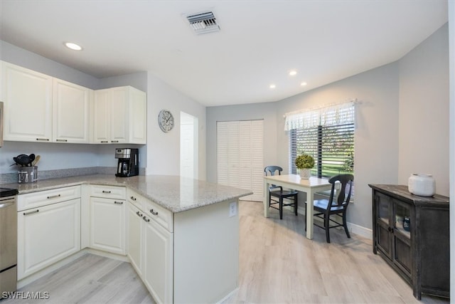 kitchen with light wood finished floors, visible vents, light stone counters, a peninsula, and white cabinets