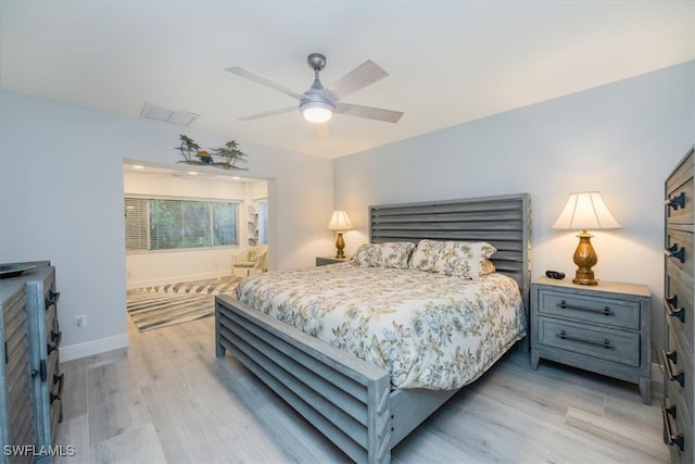 bedroom featuring a ceiling fan, light wood-style floors, visible vents, and baseboards