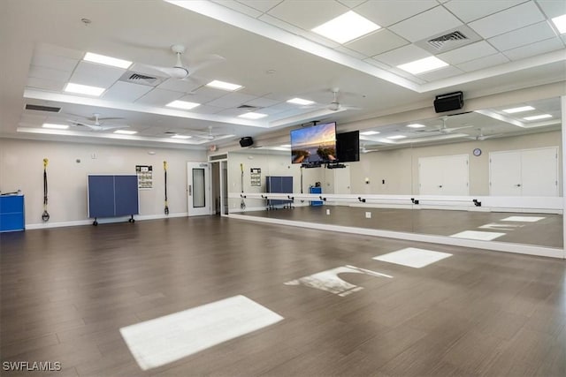 exercise room with a drop ceiling, visible vents, wood finished floors, and a ceiling fan