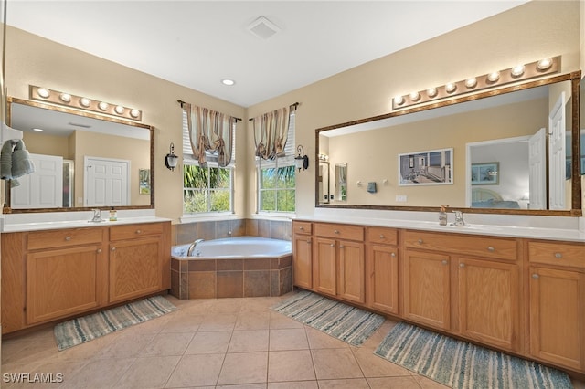 bathroom with tile patterned flooring, a relaxing tiled tub, and vanity