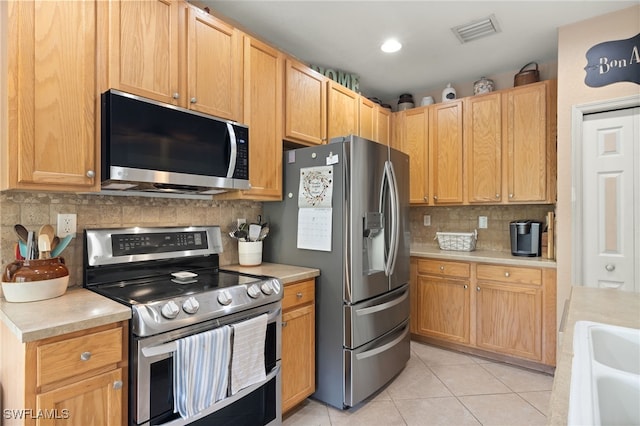 kitchen featuring decorative backsplash, light tile patterned floors, and stainless steel appliances