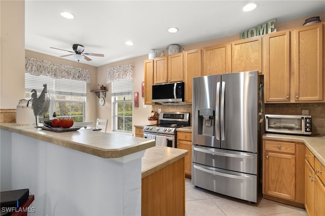 kitchen featuring ceiling fan, light tile patterned floors, appliances with stainless steel finishes, tasteful backsplash, and kitchen peninsula