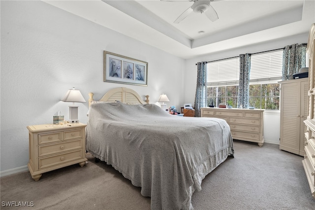 bedroom featuring ceiling fan, a raised ceiling, and carpet floors