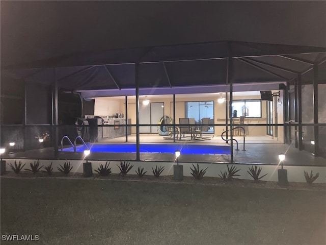 pool at twilight featuring glass enclosure and a patio area