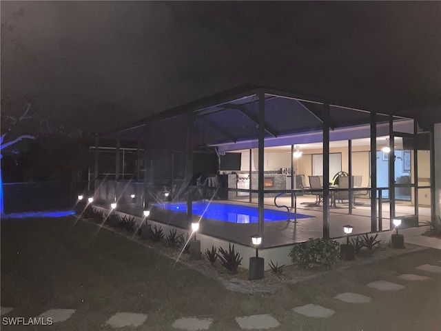 pool at twilight with a lanai and a patio area