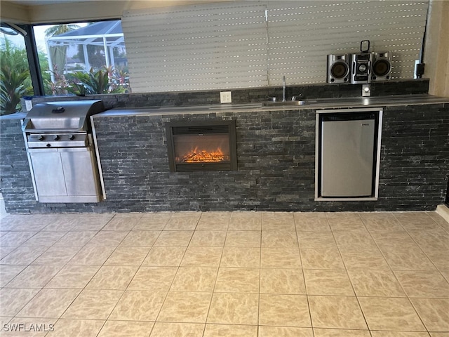 view of patio / terrace with a lanai, area for grilling, a grill, and sink