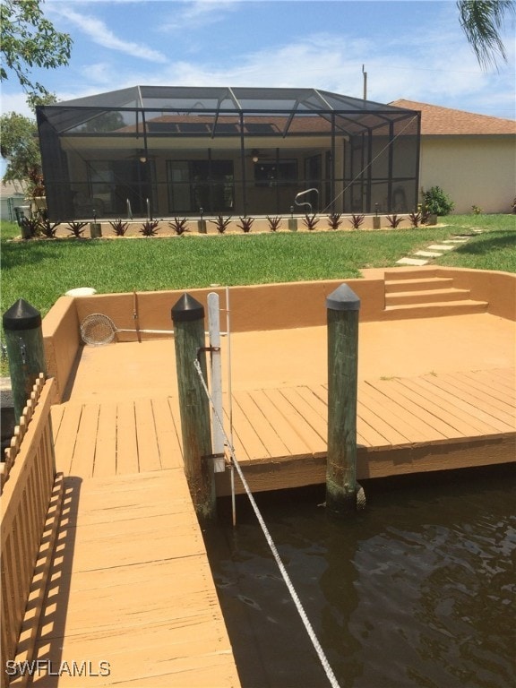 view of dock with a lawn and glass enclosure