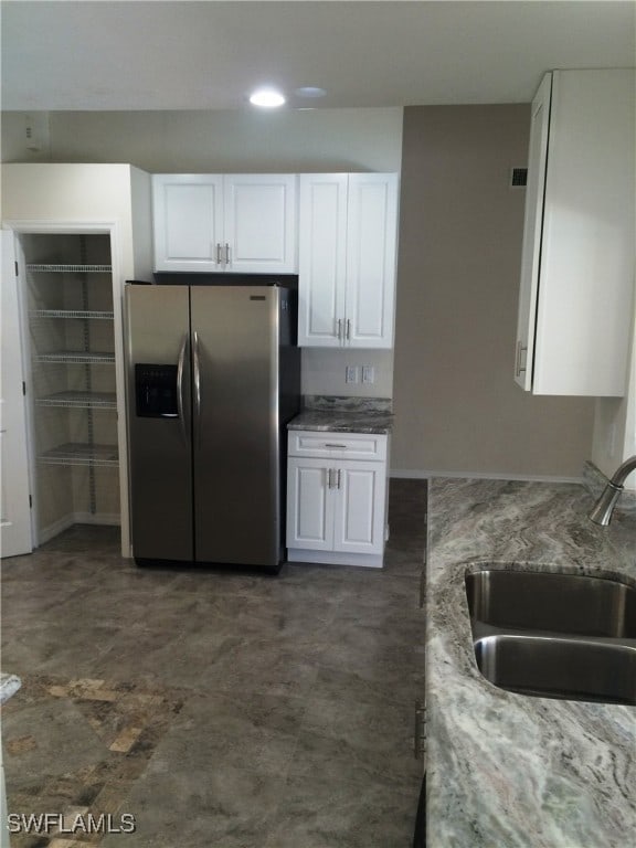 kitchen featuring white cabinetry, light stone counters, stainless steel fridge with ice dispenser, and sink