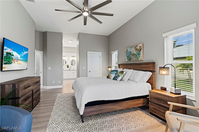 bedroom featuring connected bathroom, ceiling fan, light hardwood / wood-style flooring, and high vaulted ceiling