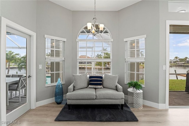 sitting room featuring a water view, light hardwood / wood-style flooring, and a notable chandelier