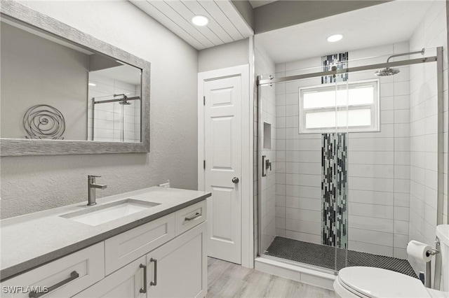 bathroom featuring wood-type flooring, vanity, toilet, and an enclosed shower